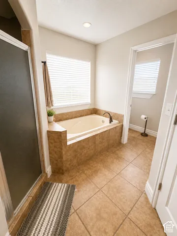 Tiled soaking tub surround with a window featuring horizontal blinds