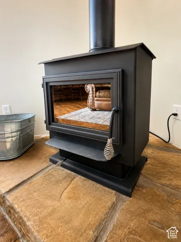 Black wood stove with a glass door, set on a natural stone hearth, featuring a black stovepipe and a textured handle