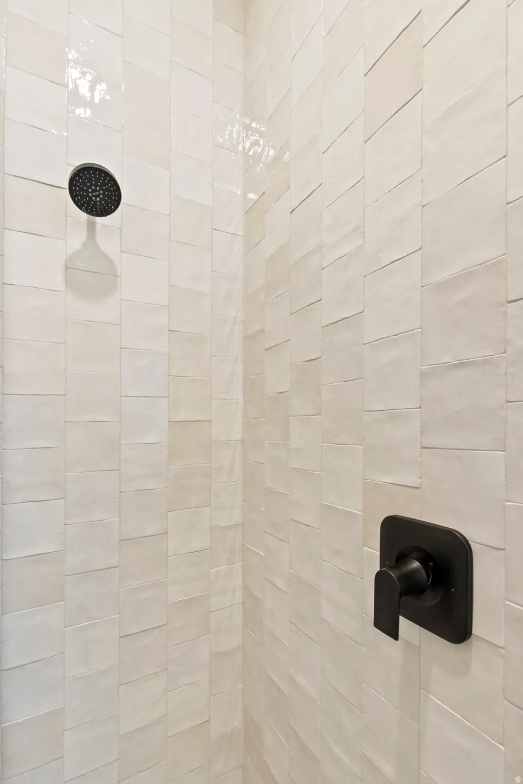 Shower enclosure with textured rectangular wall tiles and matte black fixtures