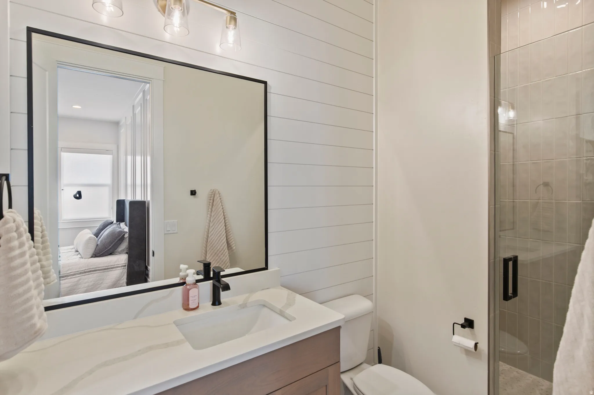 Bathroom featuring a vanity with an integrated sink, a quartz-finish countertop, and a black-framed mirror