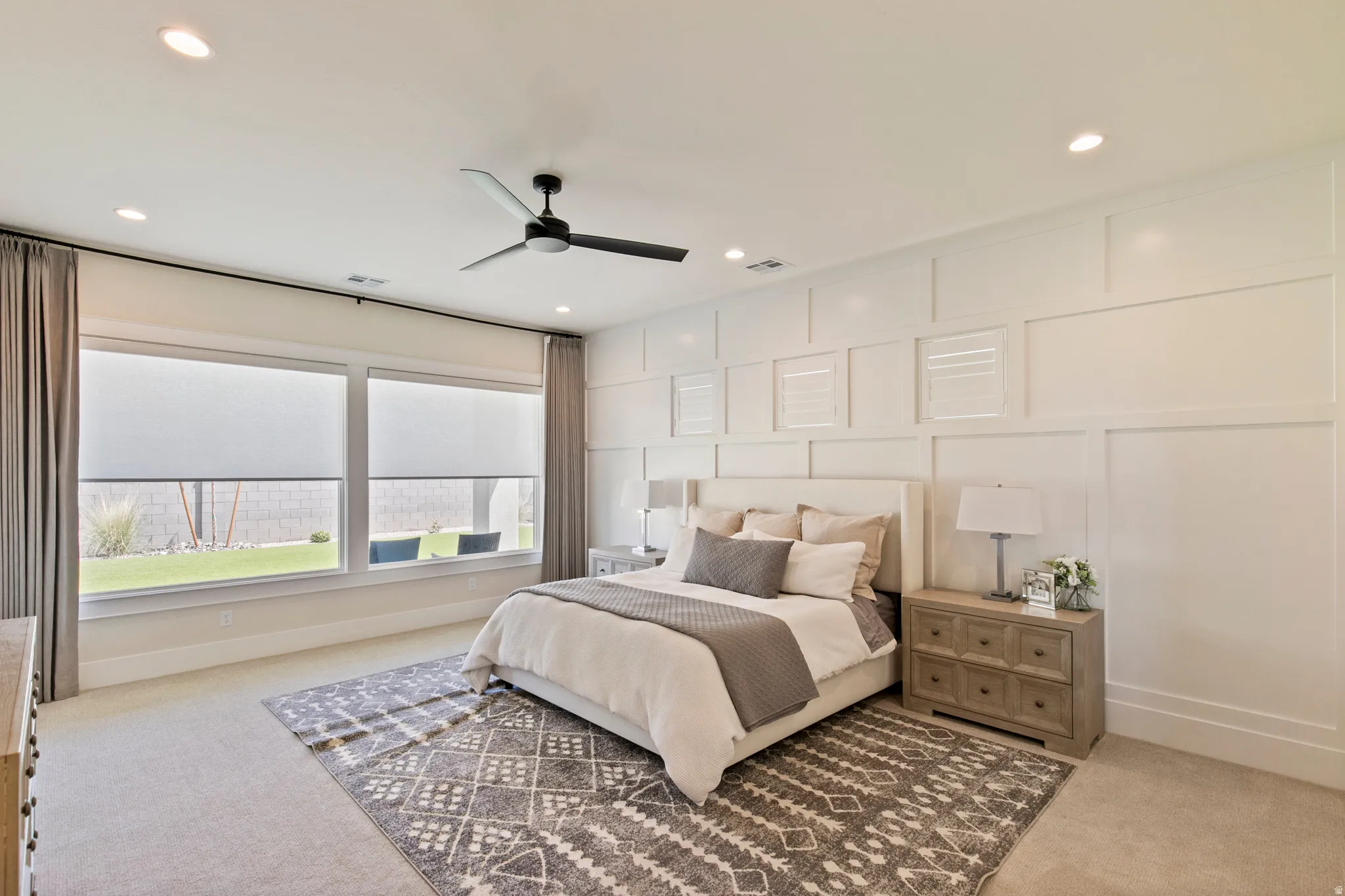 Expansive bedroom featuring large windows, recessed lighting, a ceiling fan, and panel molding on the wall