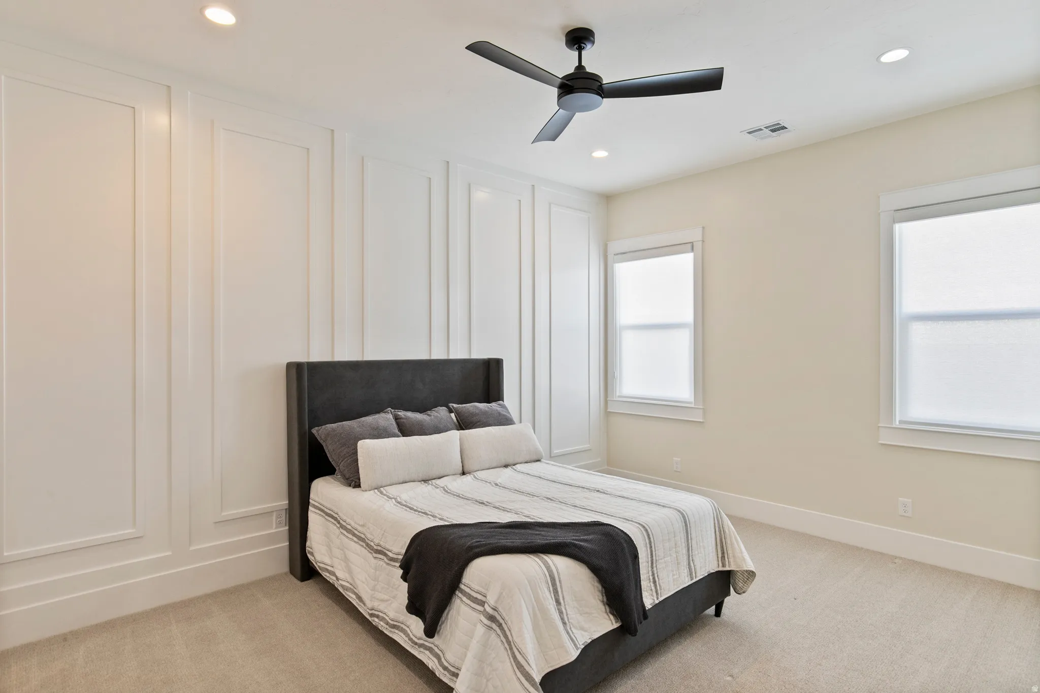 Bedroom featuring a decorative accent wall with vertical panel molding