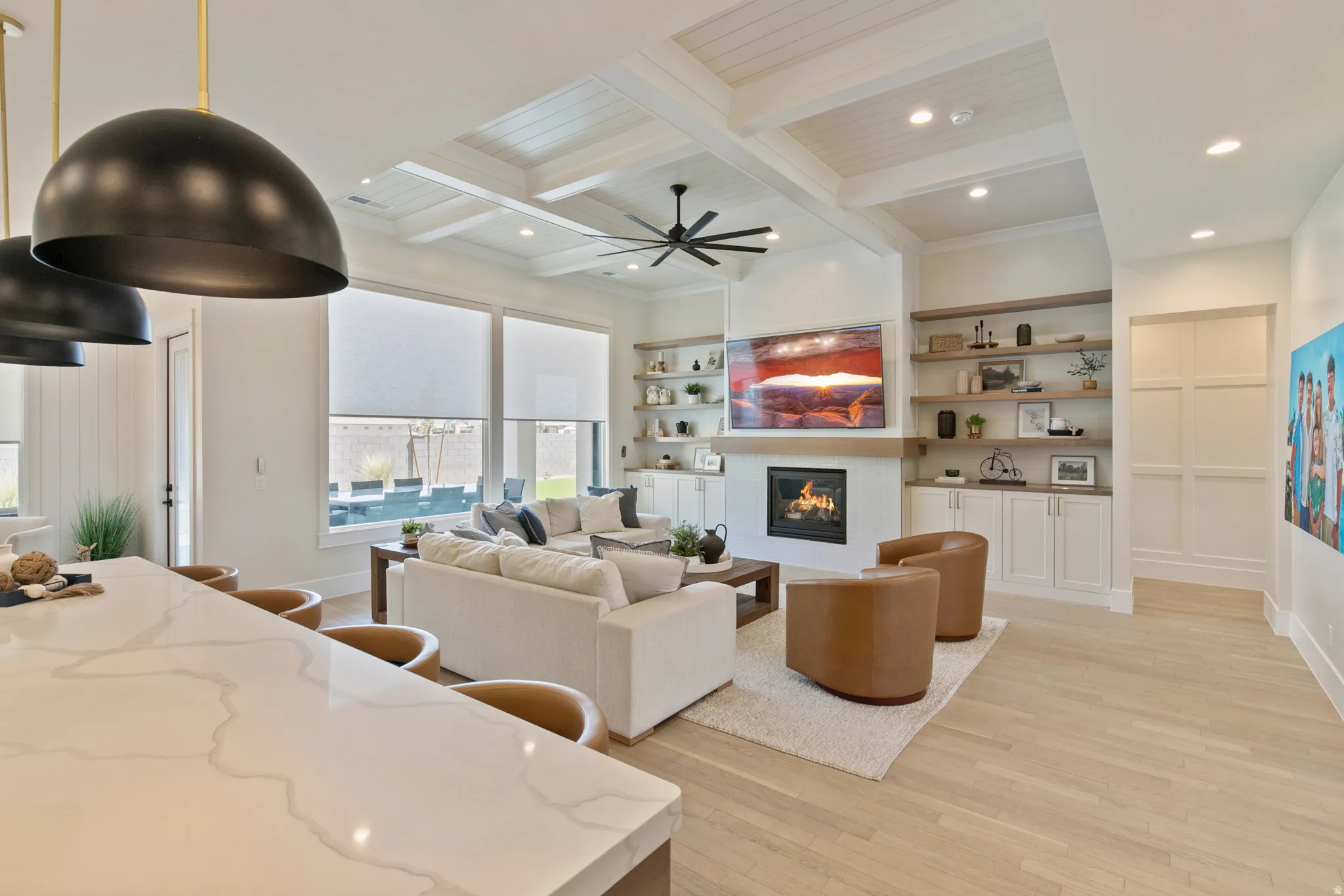 Open-concept living area featuring a coffered ceiling, wood-finish flooring, and expansive windows