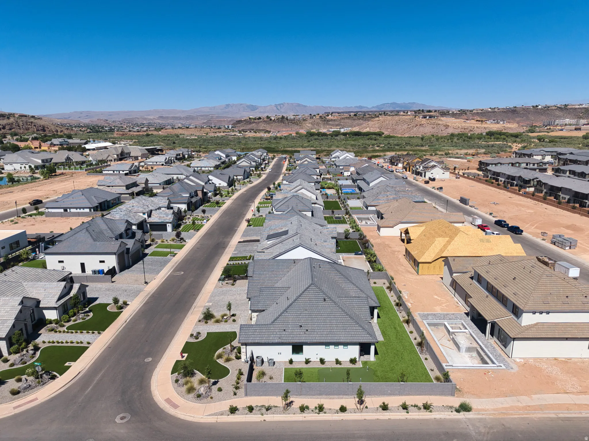 Aerial perspective of a modern residential development featuring single-story homes, structured street layout, and landscaping
