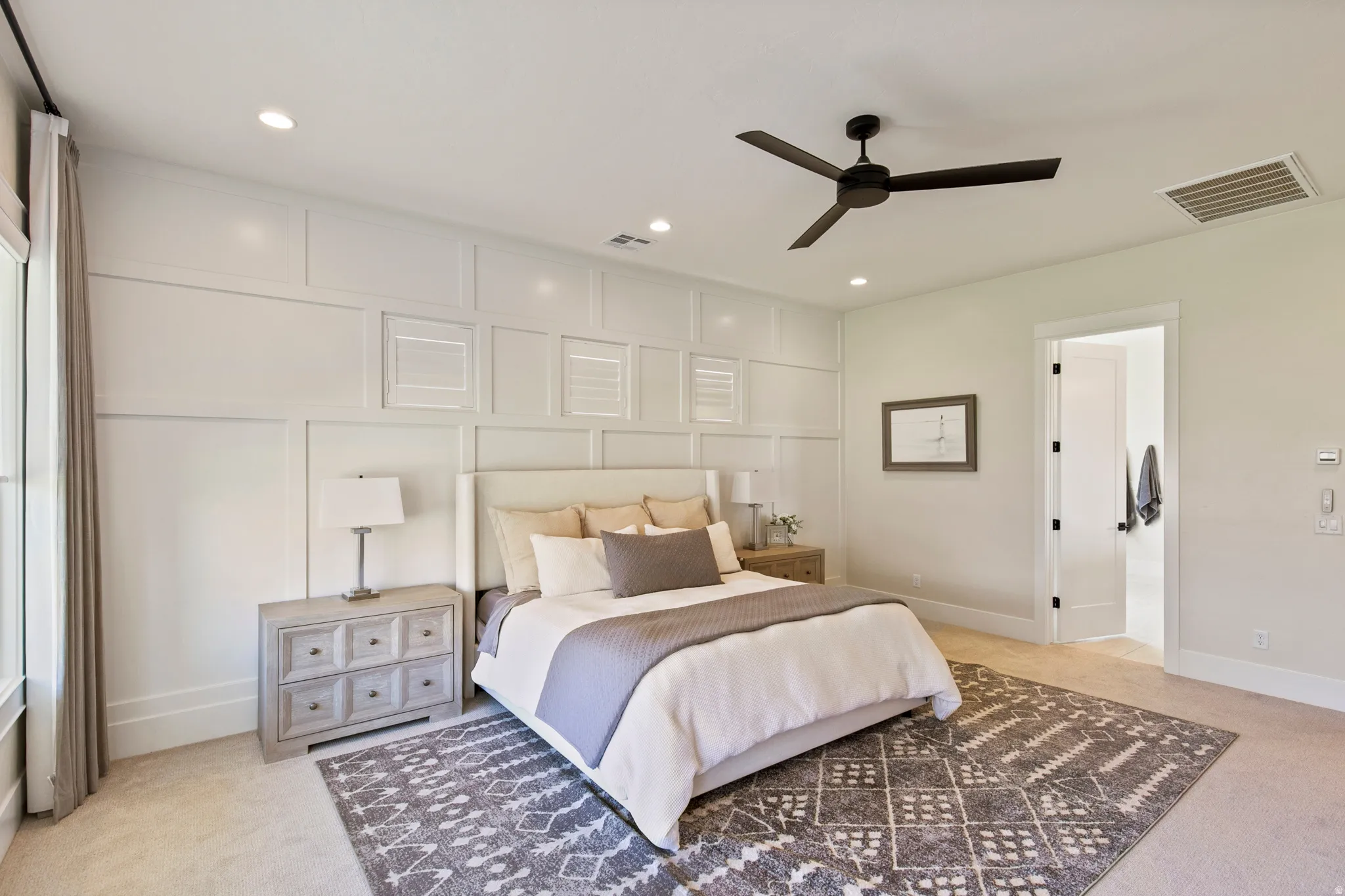 This bedroom features a white paneled accent wall, recessed lighting, and a dark ceiling fan