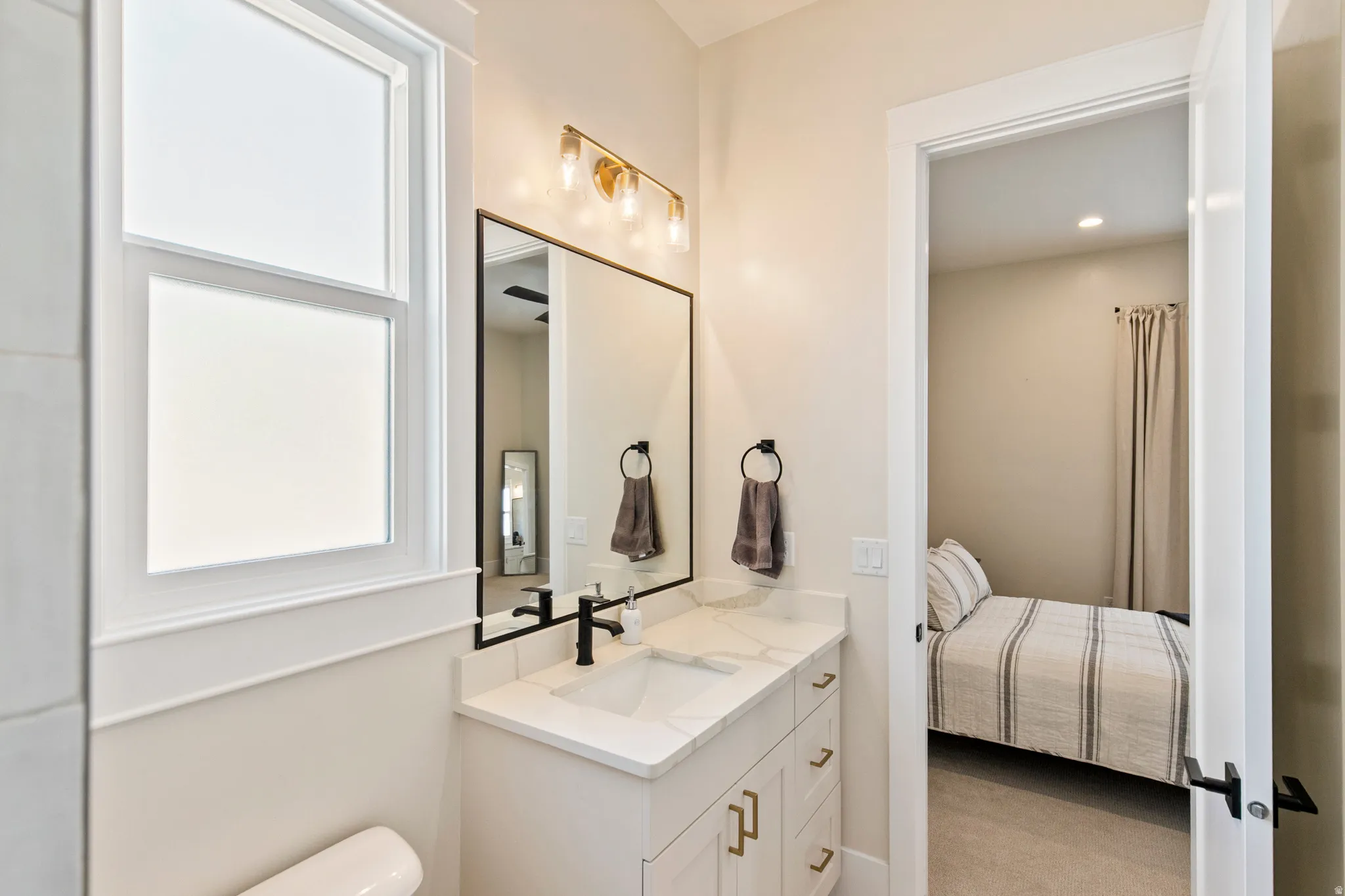 Bathroom vanity featuring a rectangular undermount sink, quartz countertop, and matte black faucet