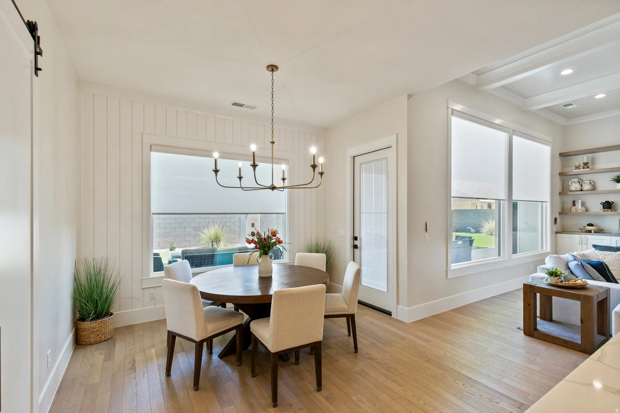 Dining area featuring a modern chandelier, light wood-finish flooring, and white shiplap accent wall