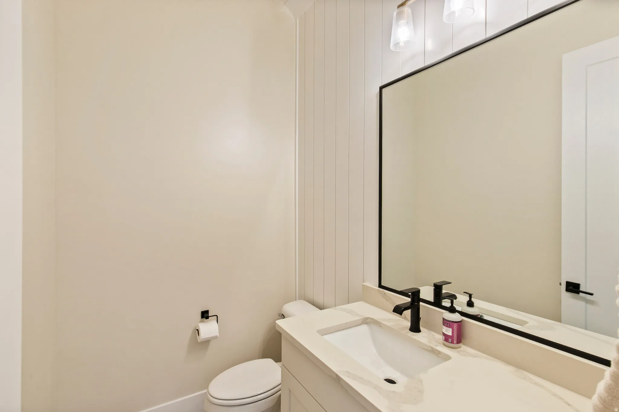 Vanity featuring an integrated rectangular sink, stone countertop, matte black faucet, and a wall-mounted mirror with a black frame