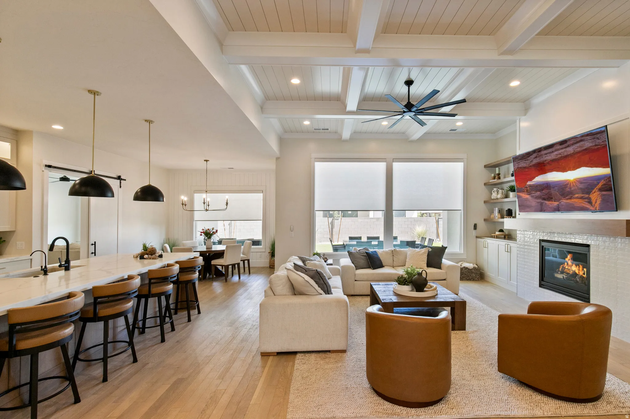 Open-concept living space featuring wood-finish flooring, a coffered ceiling with recessed lighting, and a modern ceiling fan
