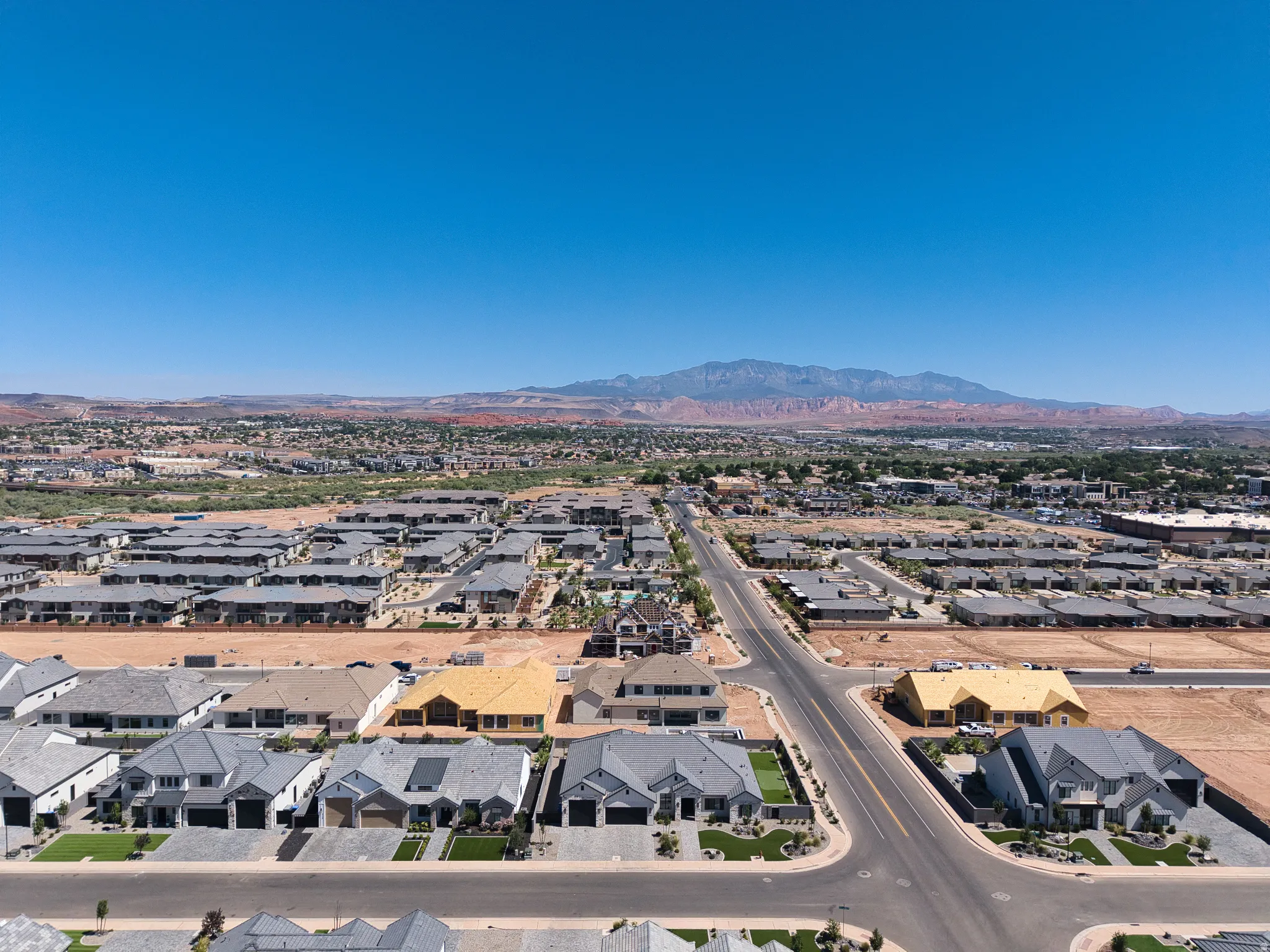 Aerial perspective showcasing an expansive residential development with numerous single-family homes and townhomes under construction