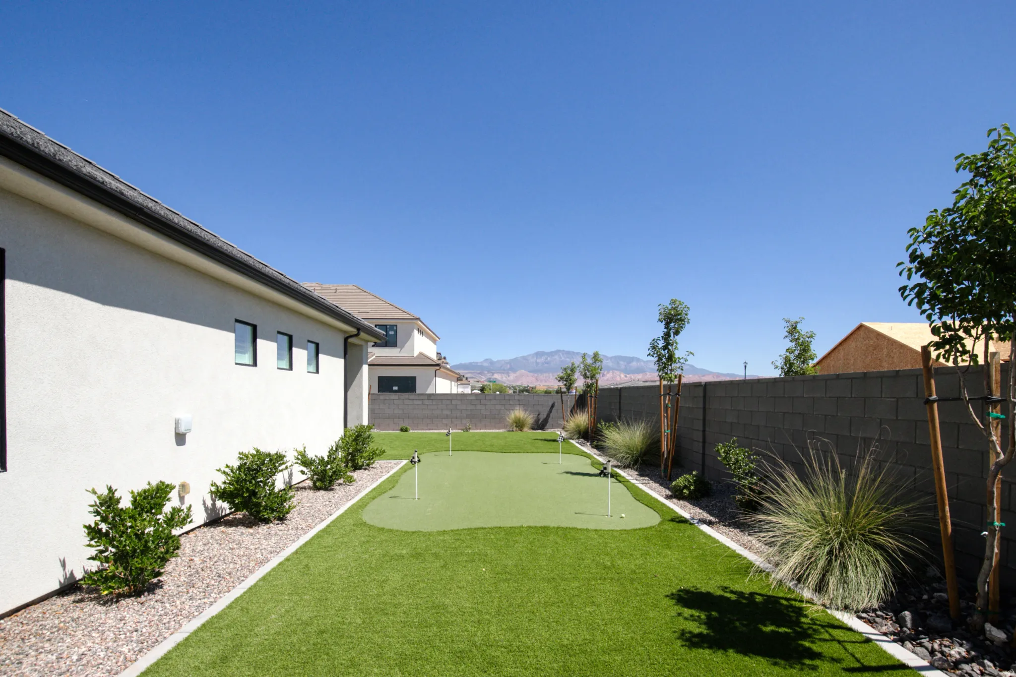 Artificial turf putting green, surrounded by decorative gravel and mature plantings