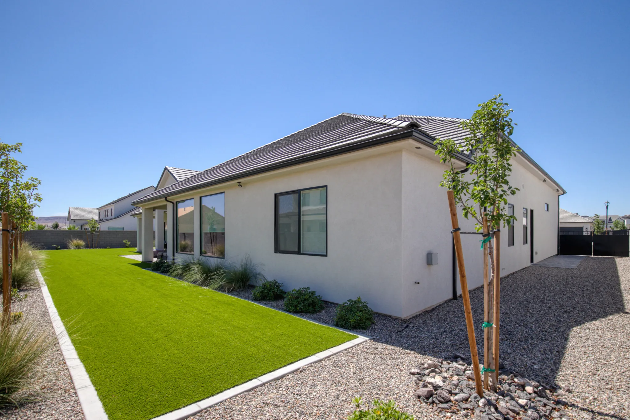 Exterior featuring a stucco finish, dark tile roof, and black-framed windows