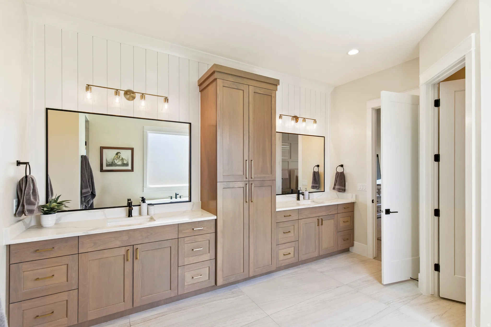 Double vanity with light wood-finish cabinetry, white countertops, and black fixtures