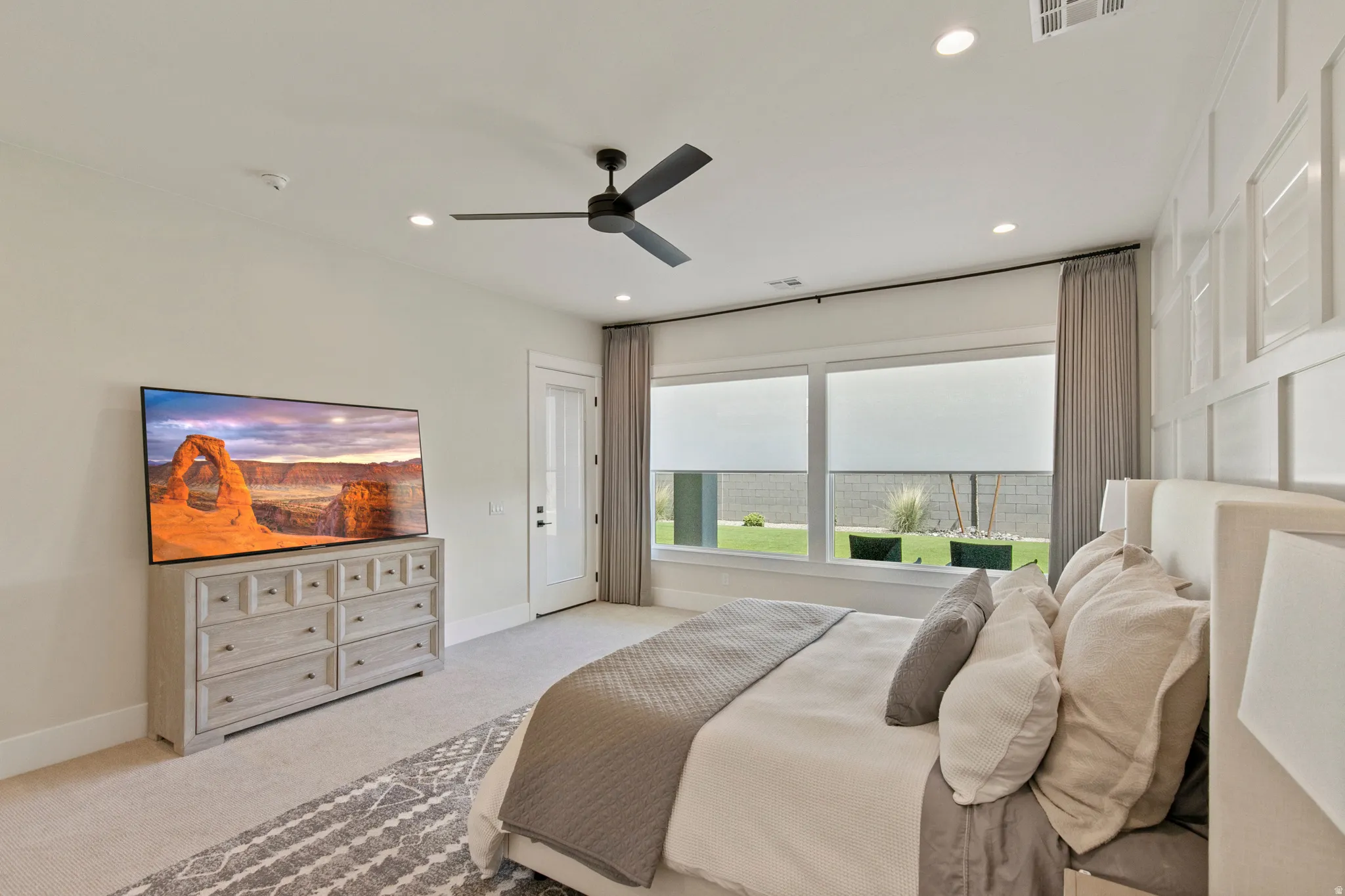 Spacious room featuring recessed lighting, a ceiling fan, large windows with roller shades, and a paneled accent wall
