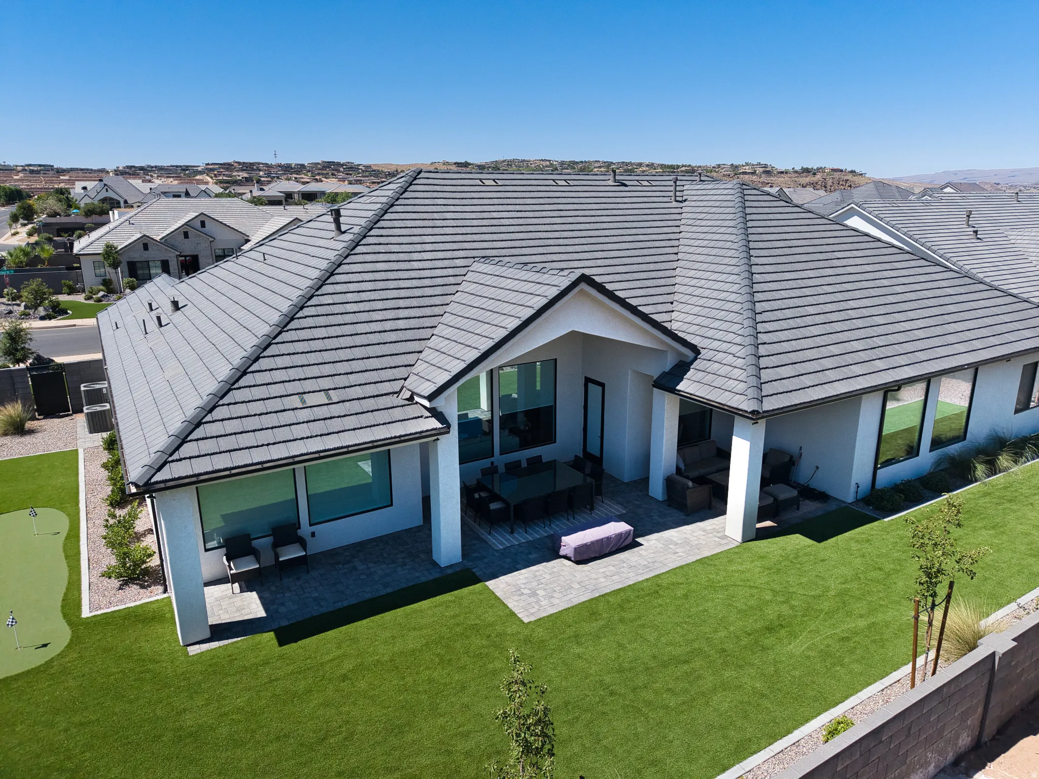 Expansive rear exterior featuring a covered patio with paved flooring