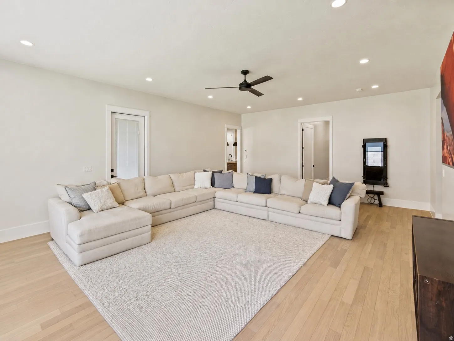 Spacious living area featuring light wood-finish flooring, white walls, and recessed lighting