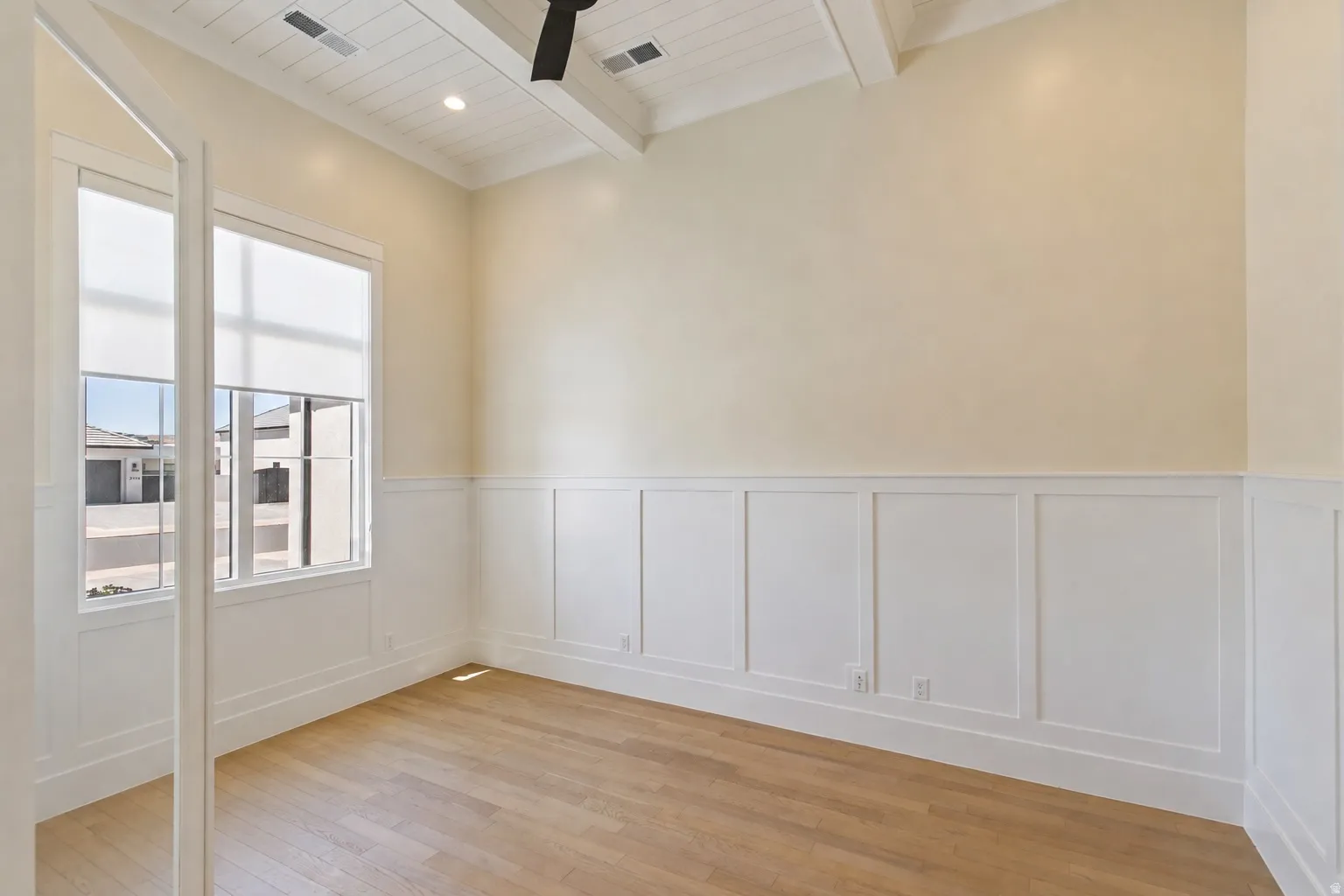 Room featuring wood-finish flooring, wainscoting, a vaulted ceiling with exposed beams, recessed lighting, and a ceiling fan