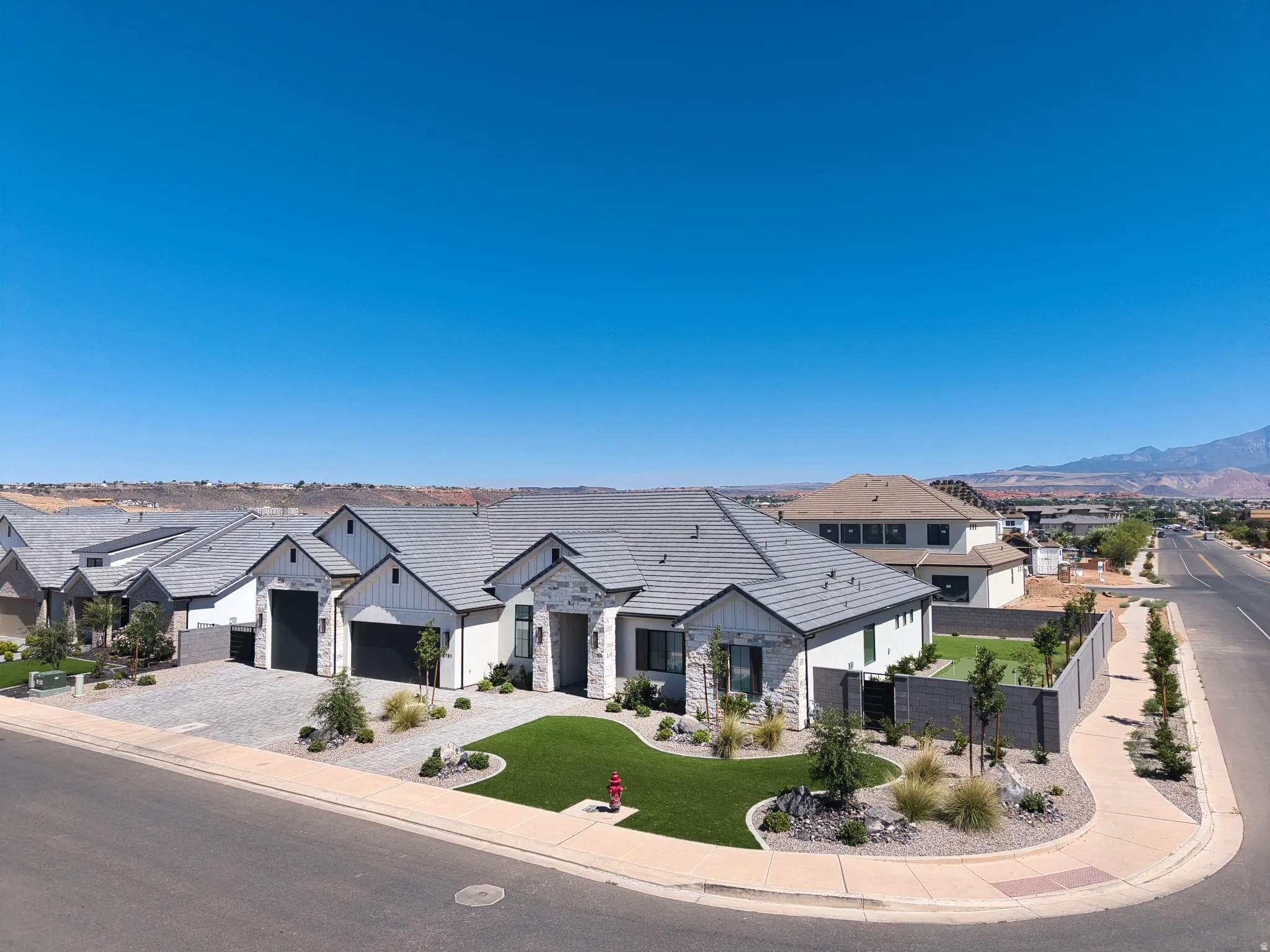 Contemporary stucco and stone exterior featuring a grey tile roof and a two-car garage