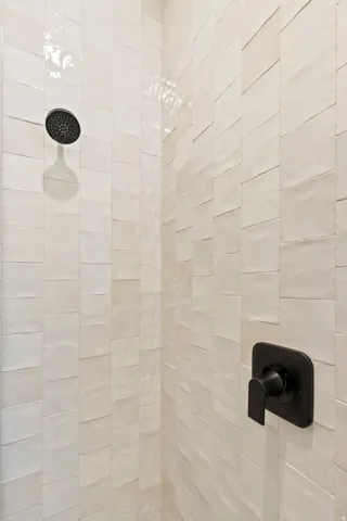 Shower enclosure with textured rectangular wall tiles and matte black fixtures