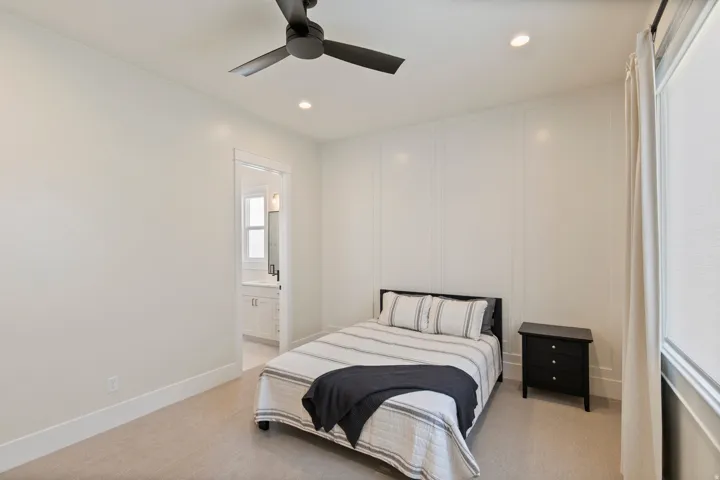 Bedroom featuring white paneled accent wall, recessed lighting, and a modern ceiling fan