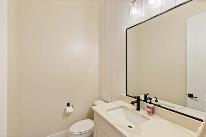 Vanity featuring an integrated rectangular sink, stone countertop, matte black faucet, and a wall-mounted mirror with a black frame