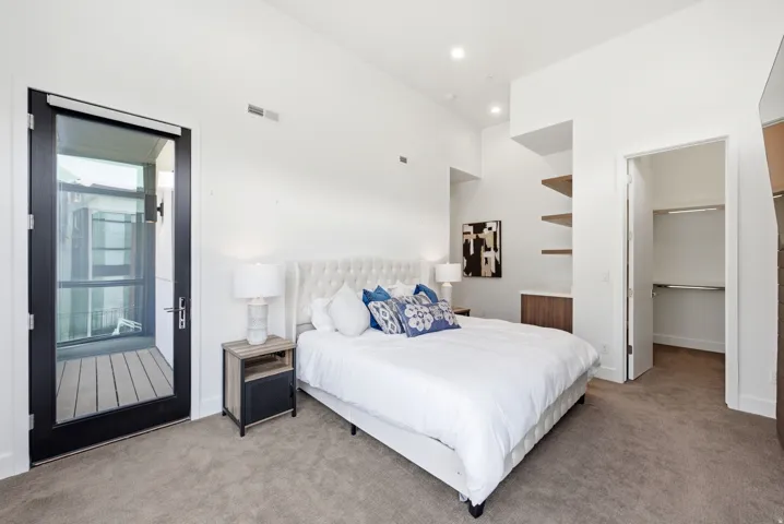 Bedroom featuring a full-light exterior door to a balcony, recessed lighting, vaulted ceilings, and built-in shelving