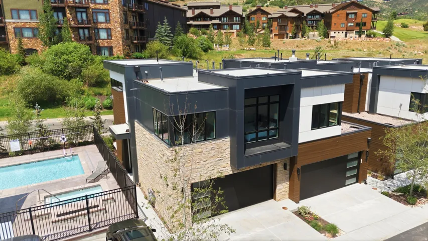 Modern architectural residence featuring a stone and dark panel facade, a flat roofline, and integrated garage doors