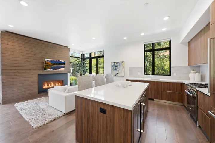 Open-concept living space featuring wood-finish flooring, a contemporary fireplace with a horizontal firebox, and recessed lighting
