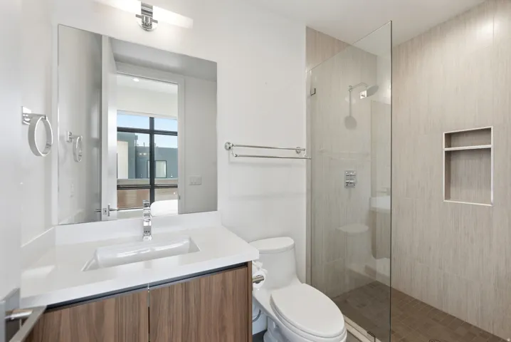 Modern bathroom featuring a single vanity with wood-finish cabinetry and a white countertop