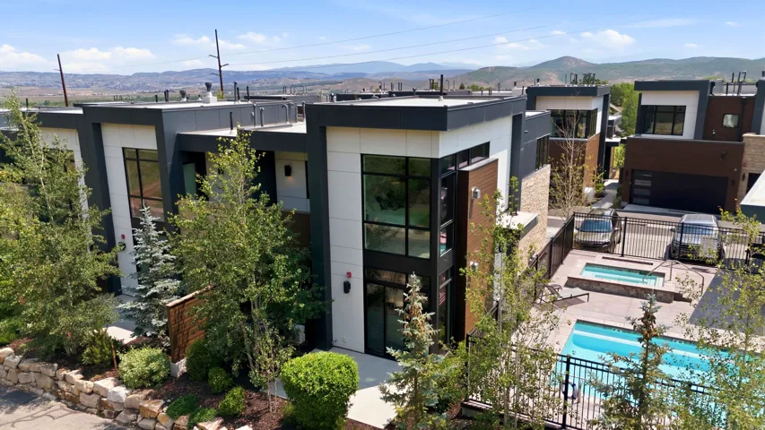 Contemporary multi-story residences featuring dark trim and light paneling, complemented by wood-finish and stone accents