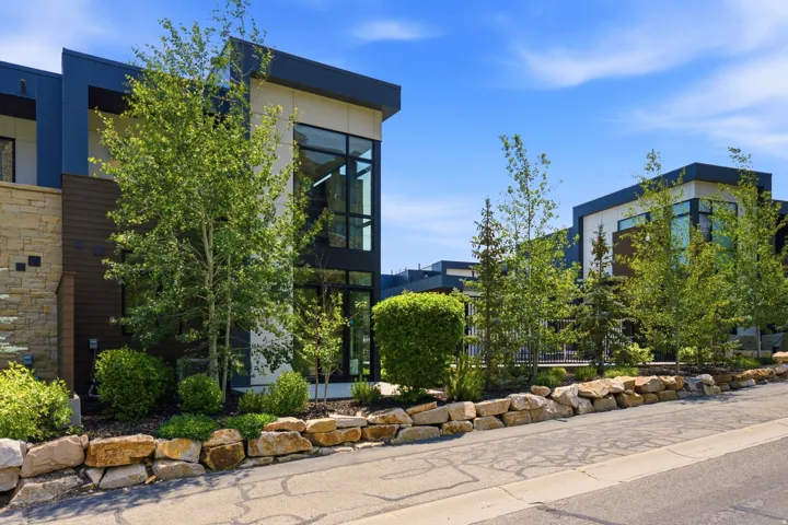 Contemporary exterior featuring a flat roofline, large format windows, and stone veneer accents