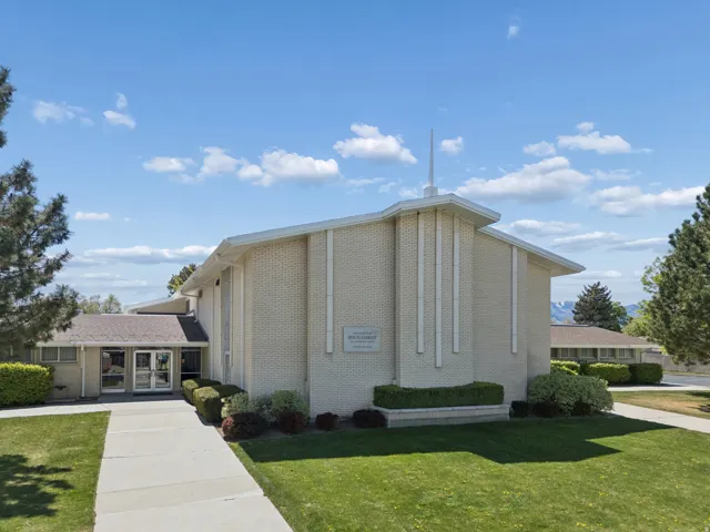 Cream brick exterior building with a prominent steeple, featuring a flat roofline and a central entrance
