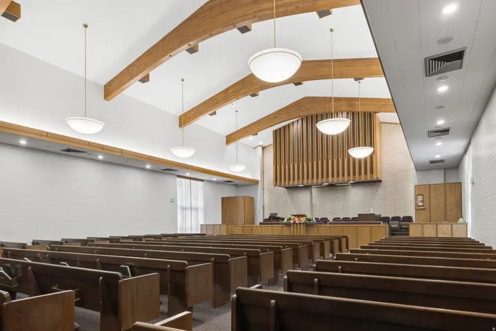 Spacious interior featuring exposed wood beams and vaulted ceilings with pendant lighting