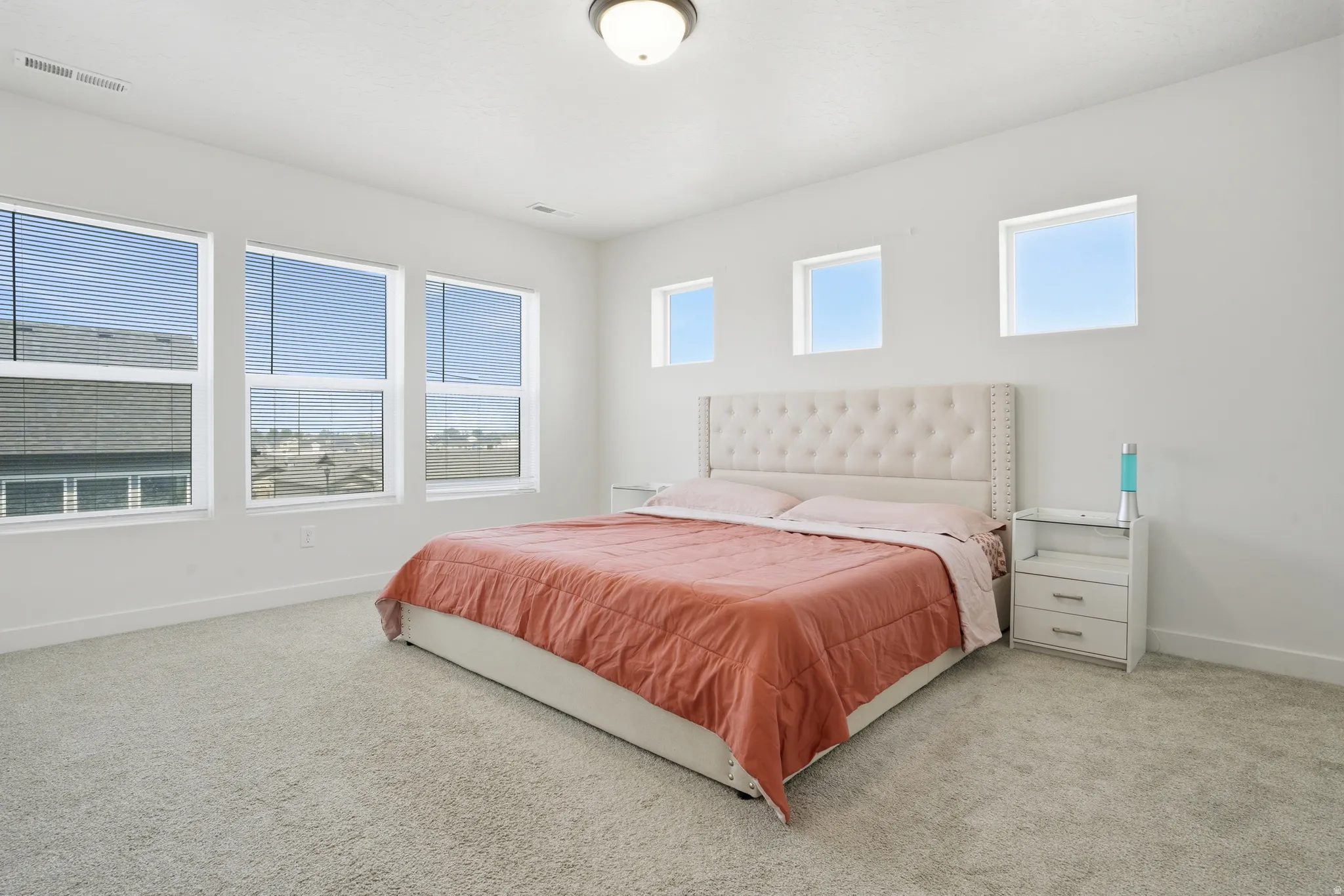 Carpeted room featuring multiple windows, white walls, and a flush-mount ceiling light fixture