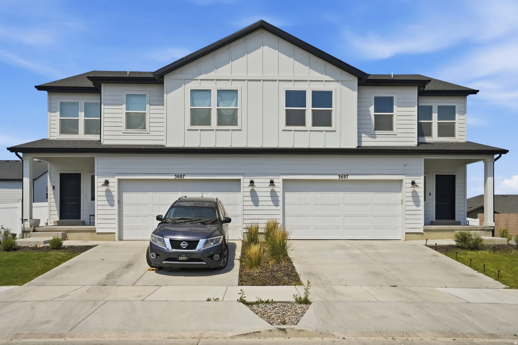 Contemporary duplex exterior featuring white board and batten siding with contrasting dark trim