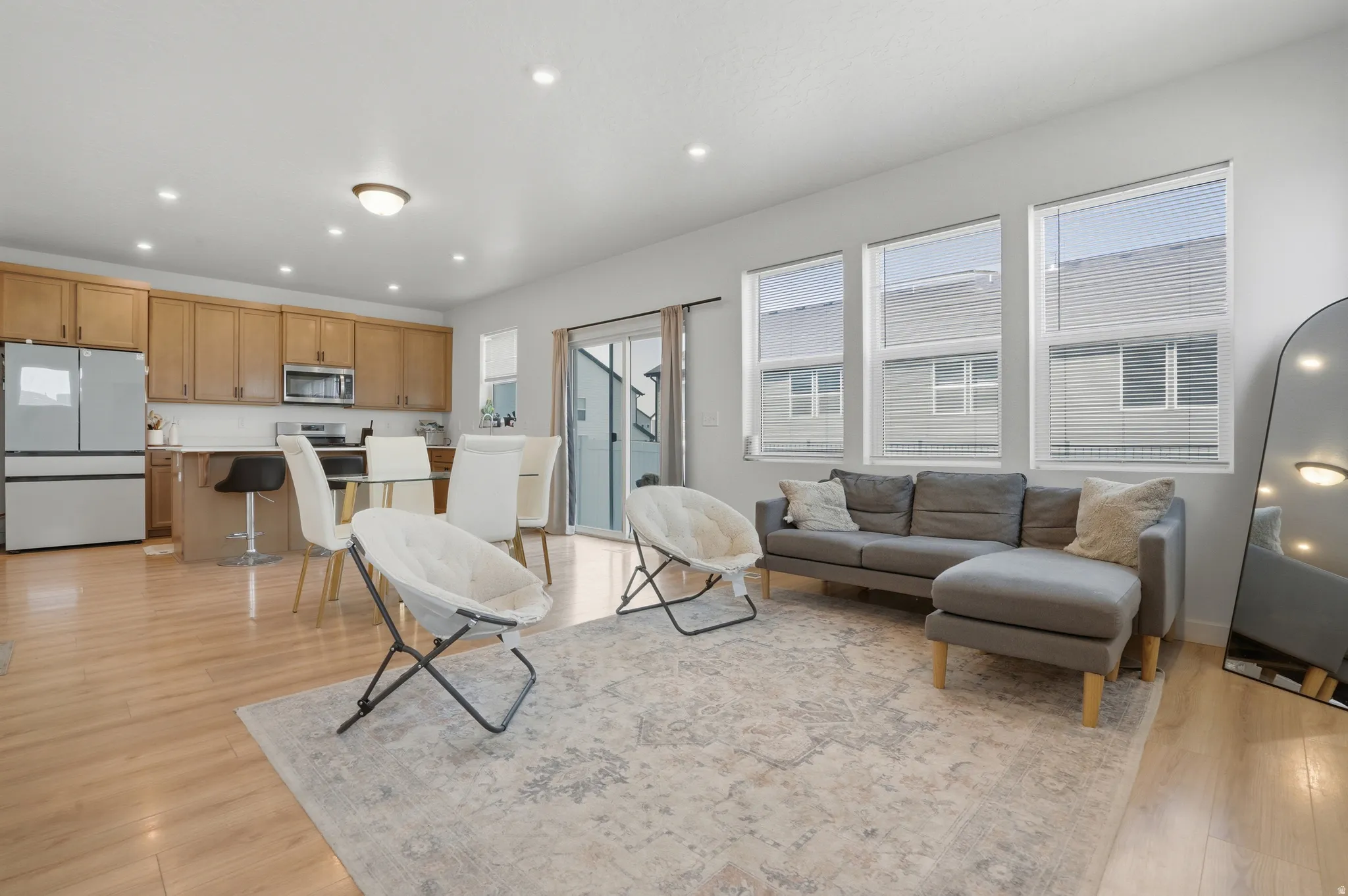 Open-concept living space with wood-finish flooring, recessed lighting, and ample natural light from multiple windows