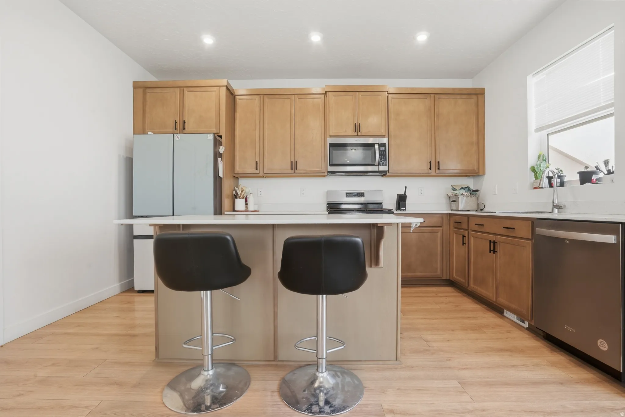 Kitchen featuring an island with countertop seating, wood-finish flooring, recessed lighting, and a white tile backsplash