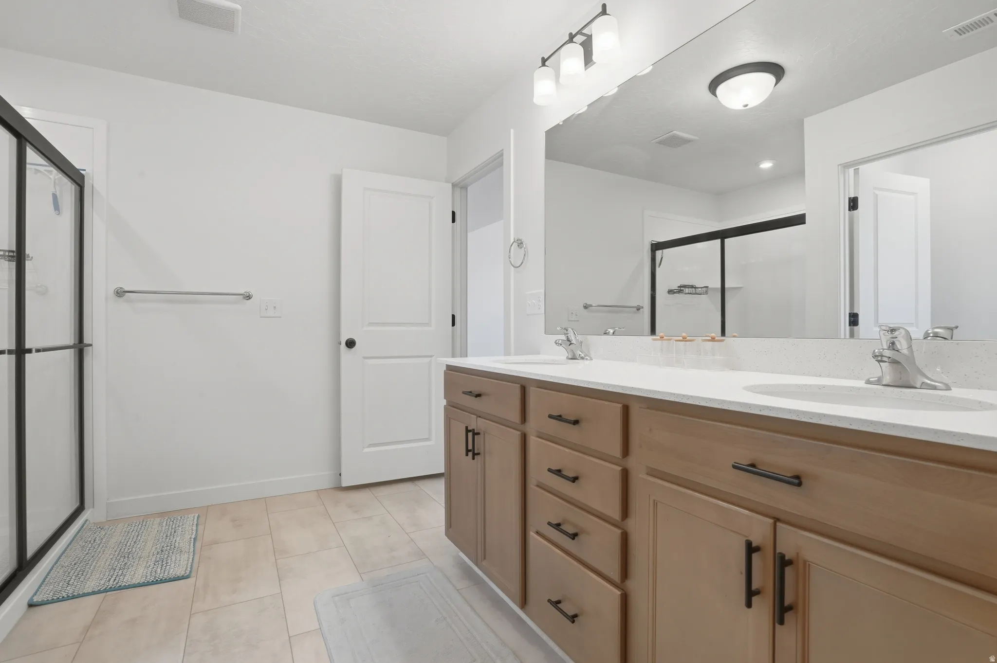 Double vanity with light wood-finish cabinetry, white countertops, and dual undermount sinks