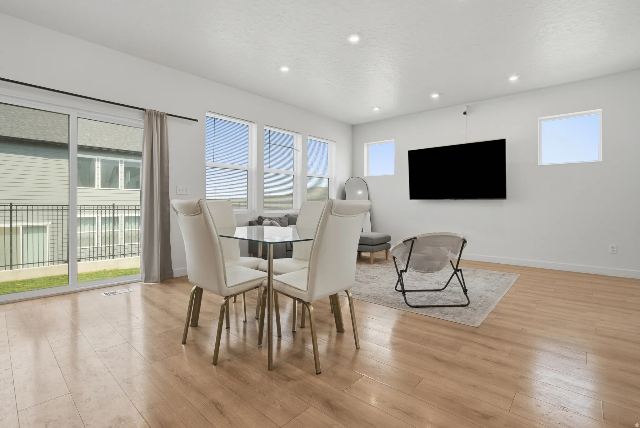 Open-concept living space with wood-finish flooring, recessed lighting, and white walls