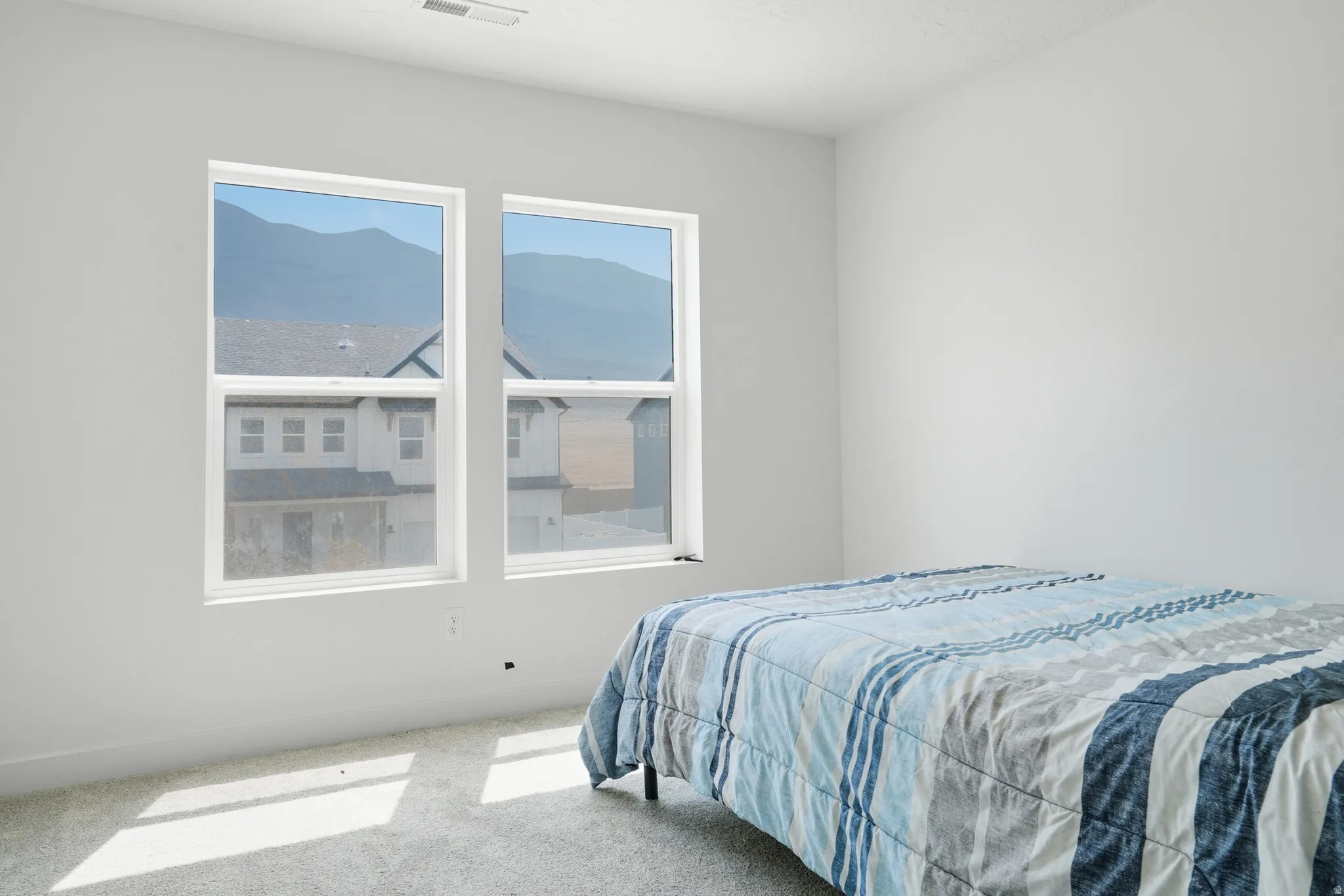 Bright room featuring two large windows with mountain scenery