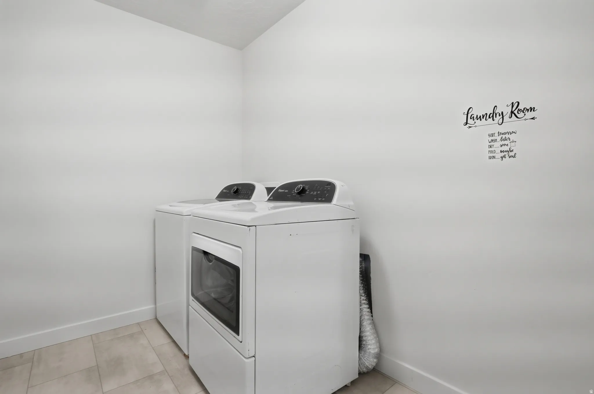 Laundry area featuring light-toned tile flooring and white baseboards