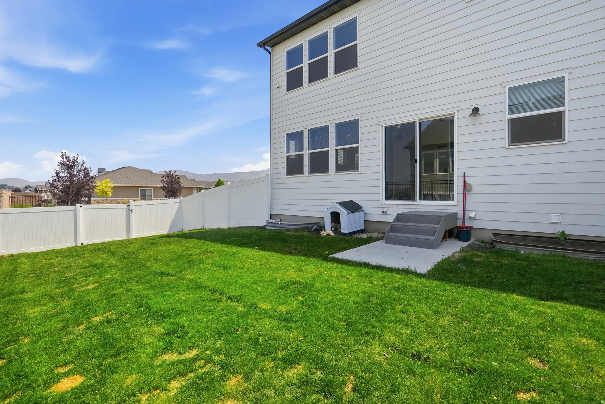 Expansive green lawn with a white vinyl fence encompassing the property