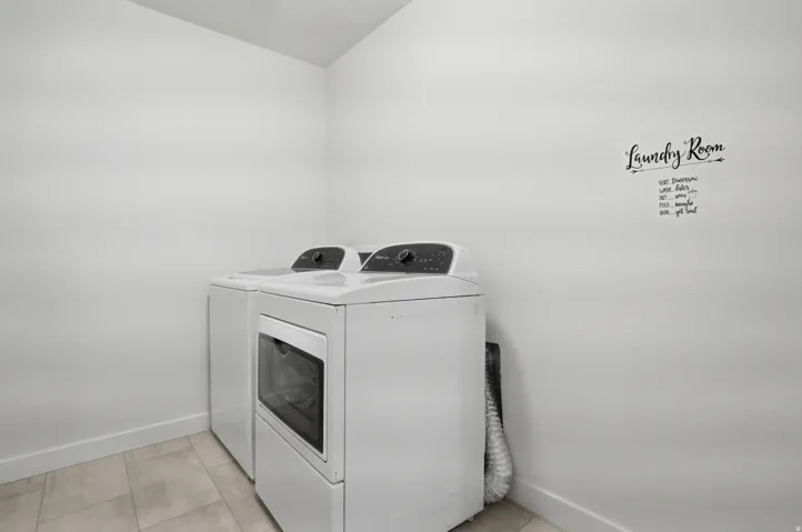 Laundry area featuring light-toned tile flooring and white baseboards