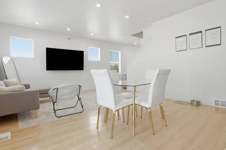 Bright open-concept living space featuring wood-finish flooring, recessed lighting, and crisp white walls