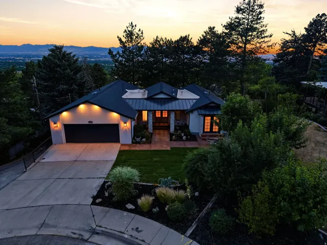 Exterior facade featuring a dark metal roof, light-toned stucco, and a black garage door