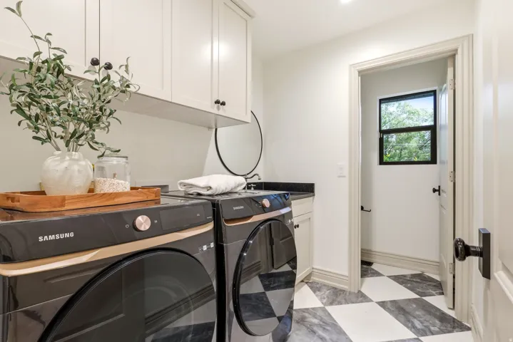 Laundry area featuring upper cabinetry, a utility sink with a dark countertop, and a checkerboard-patterned floor