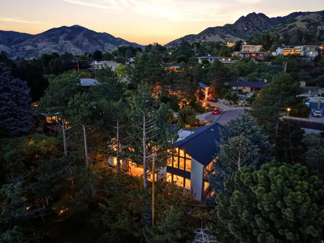 Contemporary residence showcasing a dark-pitched roof, expansive multi-story windows, and light-toned exterior siding