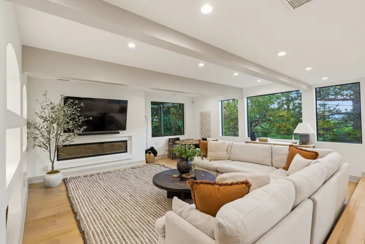 Recessed lighting illuminates this living area featuring wood-finish flooring, an inset linear fireplace, and built-in shelving