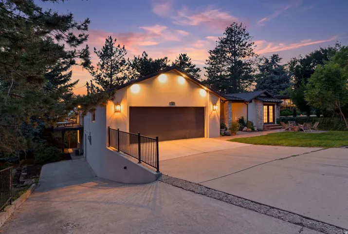 Front exterior featuring a multi-car driveway, attached garage, stone accents, and a landscaped yard