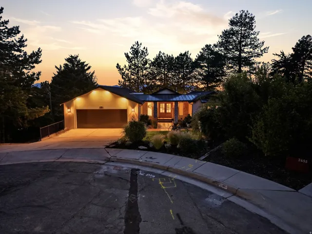 Single-level residence with an attached garage, featuring exterior lighting and a paved driveway